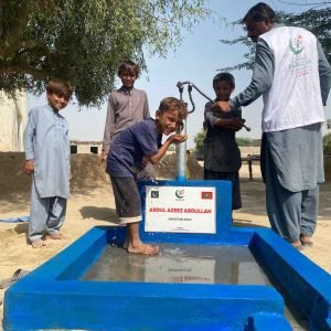 Children enjoying water from a hand pump, supported by Khubaib Foundations efforts.