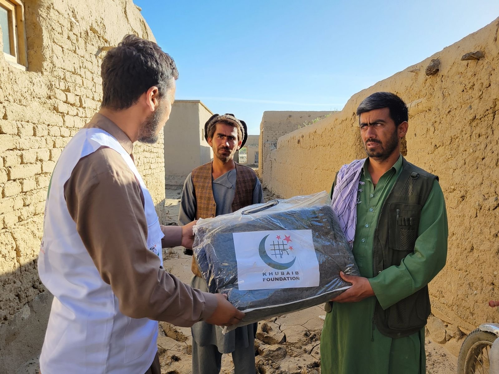 Khubaib Foundation volunteer handing over a blanket package to local men.