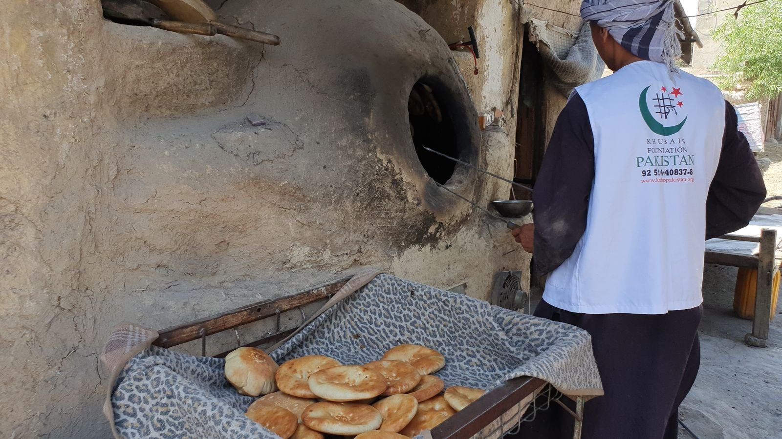 Khubaib Foundation worker baking fresh bread in a traditional tandoor.