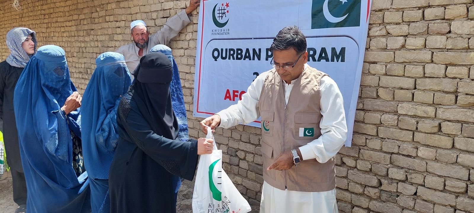 Volunteer distributing Qurban meat bags to women in Afghanistan.