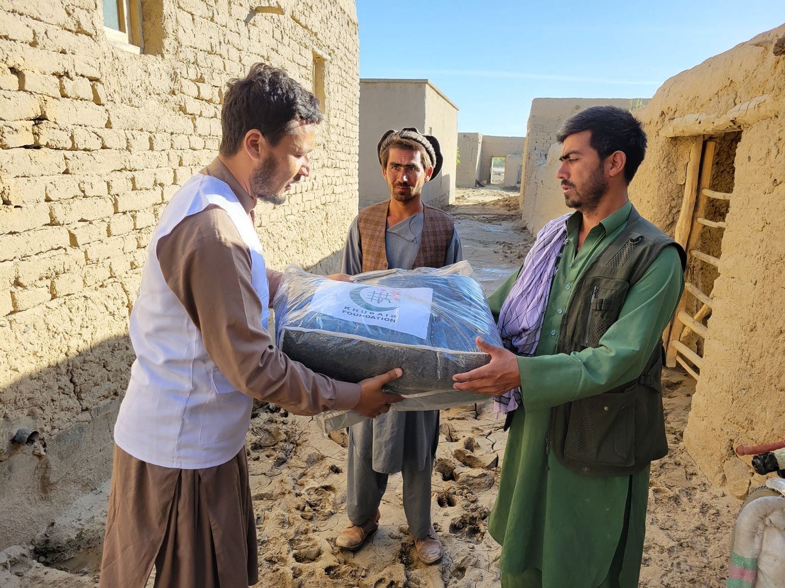 Volunteer handing over a large blanket package to local men.