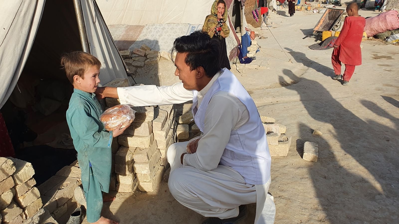 Volunteer providing food to a child at a refugee camp.