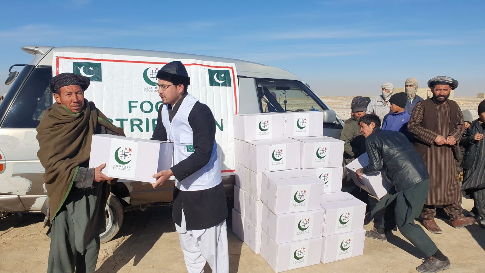 Volunteers distributing food boxes from a van in Afghanistan.